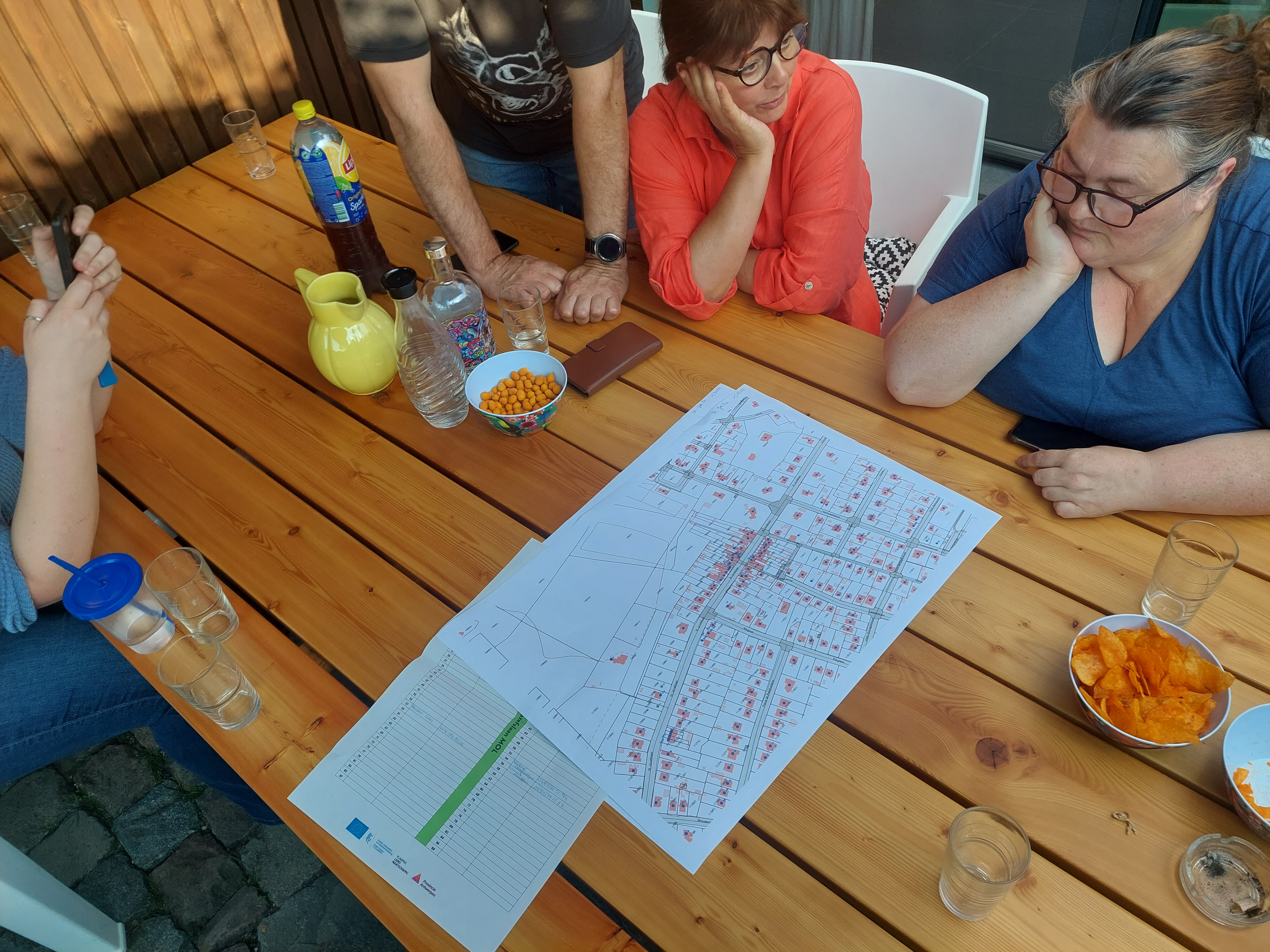 plan op tafel, mensen errond kijken er naar