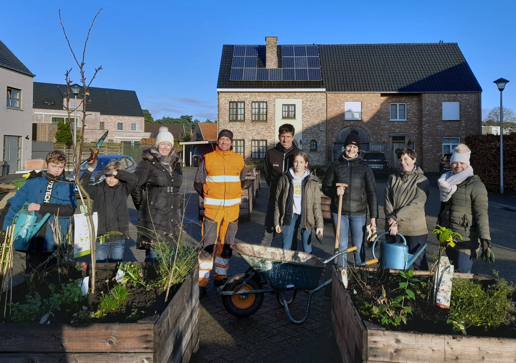 mensen met tuinmateriaal poseren voor houten bakken met plantjes