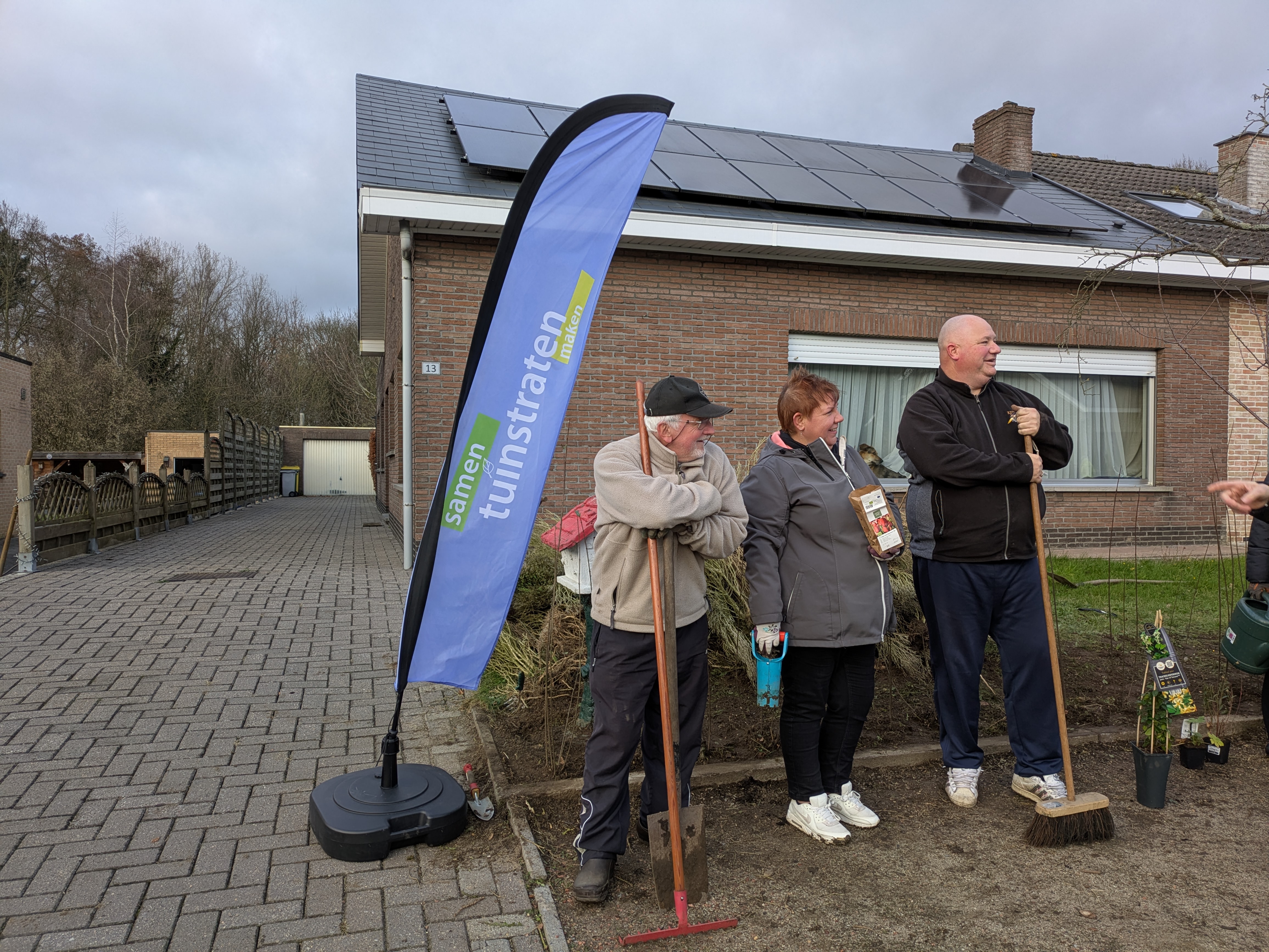 drie mensen met tuinmateriaal naast een vlag van tuinstraten