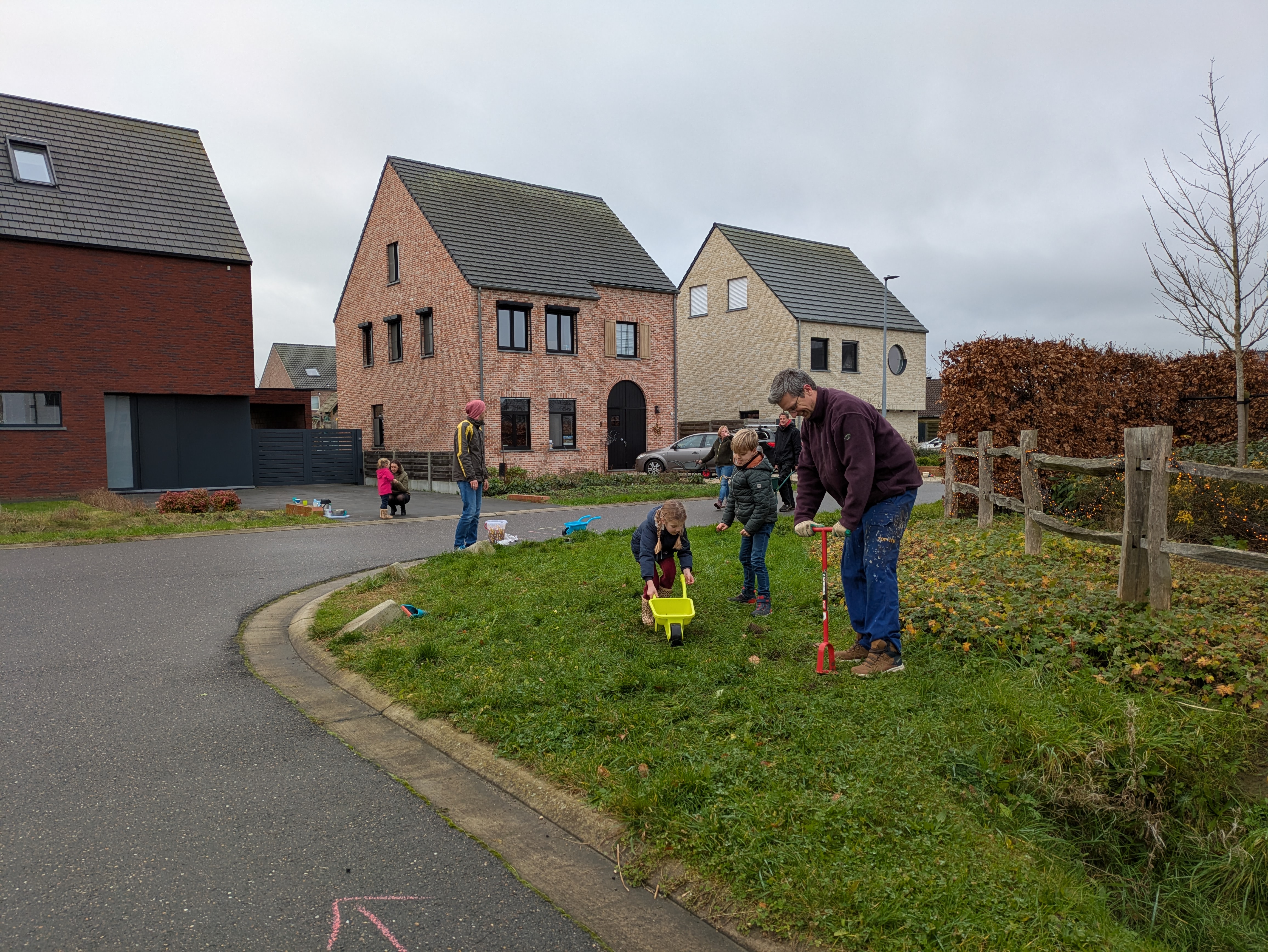 Man en kinderen planten bloembollen in de berm