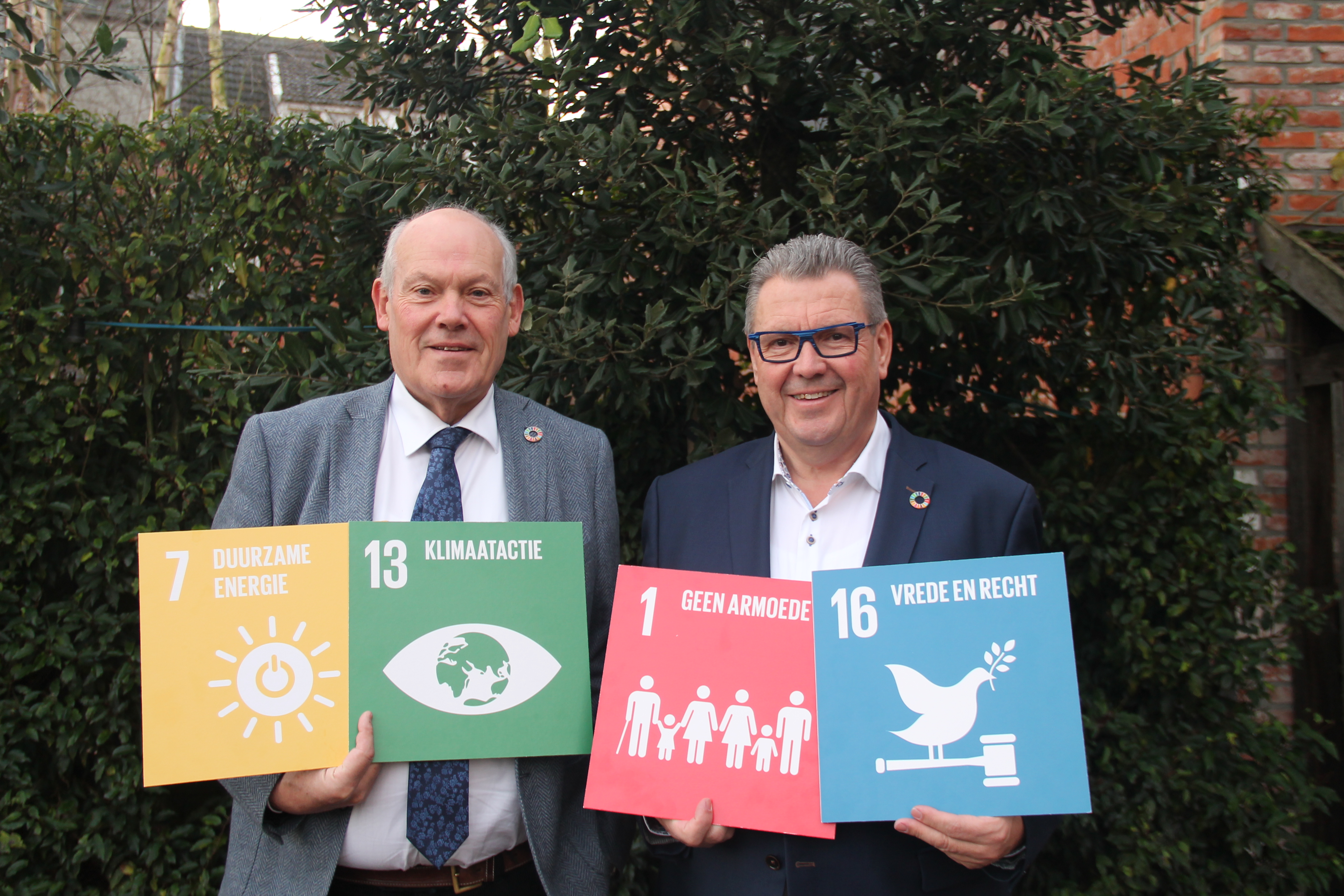 Schepen Michel Jansen en burgemeester Marc Van Aperen met enkele duurzame ontwikkelingsdoelstellingen van de VN. 