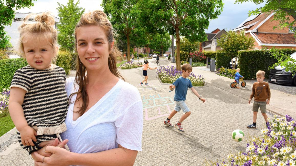 Vrouw met meisje op de arm en twee voetballende jongens op de achtergrond in een groene straat