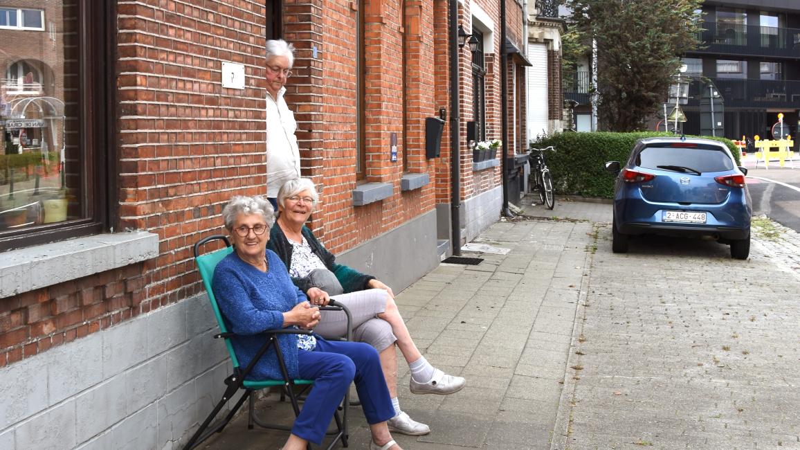 twee vrouwen op bankje voor de gevel op een grijze stoep