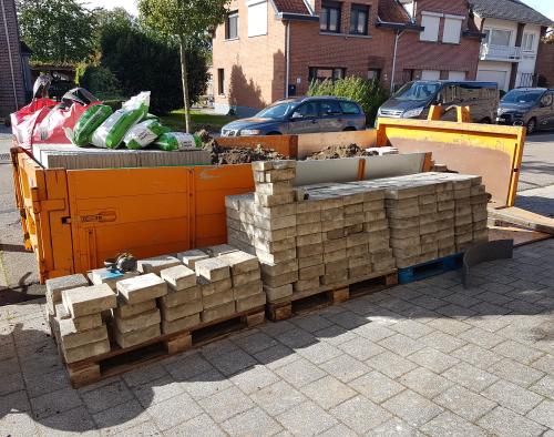 Container met stapel uitgebroken tegel ervoor