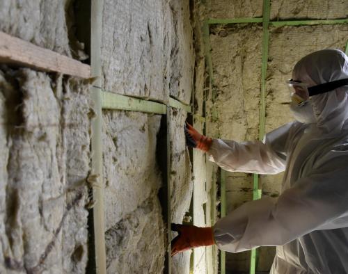 Man in wit pak isoleert zijn zoldermuur