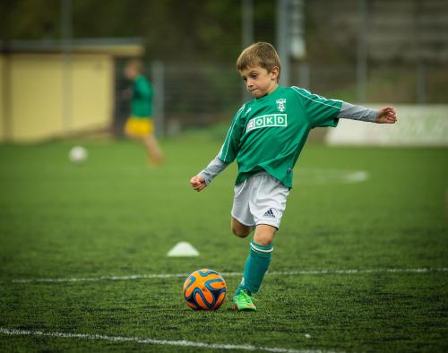 Jongetje op voetbalveld trapt tegen bal